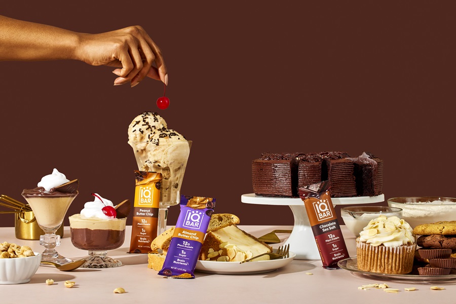 Hand topping ice cream on table full of IQBAR products