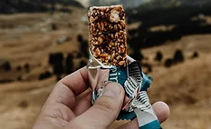 Hands holding a protein bar in the hills