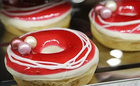 Doughnuts with a red and white frosting glaze and other confectionery items on the top.